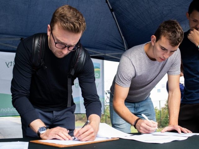 Two men standing and signing in to litter pick event
