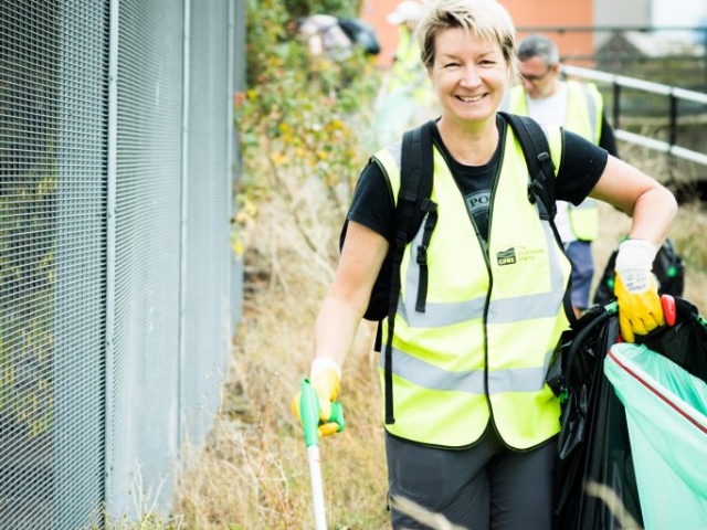 Blonde happy woman litter picking wearing hi vis jacket