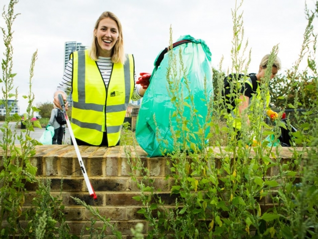 Happy woman picking litter with recycling bag